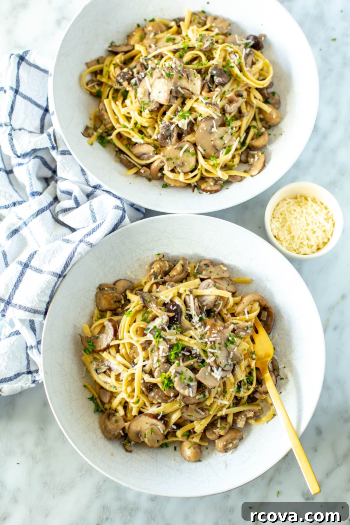 Velvety One-Pot Mushroom Pasta 2 Two generous bowls of steaming creamy mushroom pasta, perfectly garnished with fresh herbs, with a small bowl of grated parmesan cheese positioned on the side, ready for extra topping.