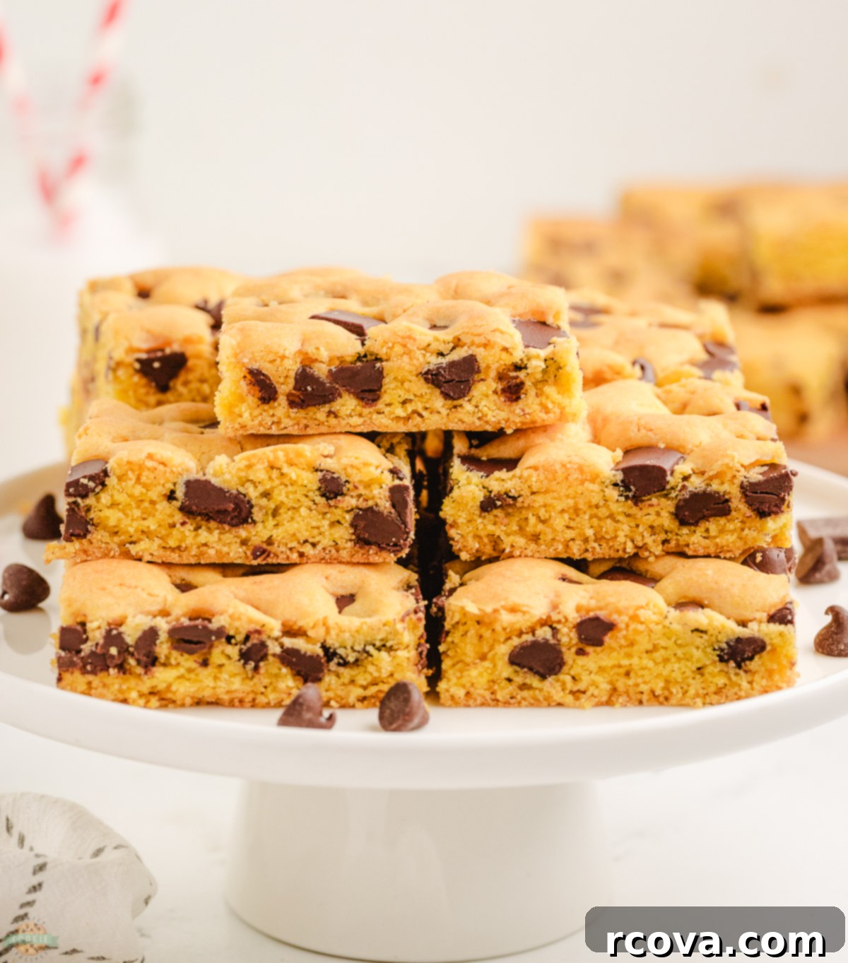 Golden Cake Mix Cookie Bar Delights 4 A beautifully arranged stack of golden chocolate chip cake mix cookie bars on a white cake stand, highlighting their soft, inviting texture and generous chocolate distribution.