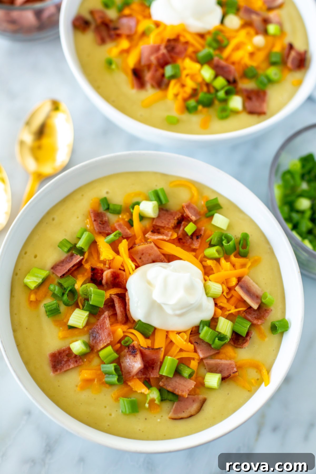 Your New Favorite Slow Cooker Potato Soup 6 A close-up of a bowl of creamy crockpot potato soup, beautifully topped with vibrant green onions, melted cheddar cheese, crispy bacon, and a dollop of sour cream, ready to eat.