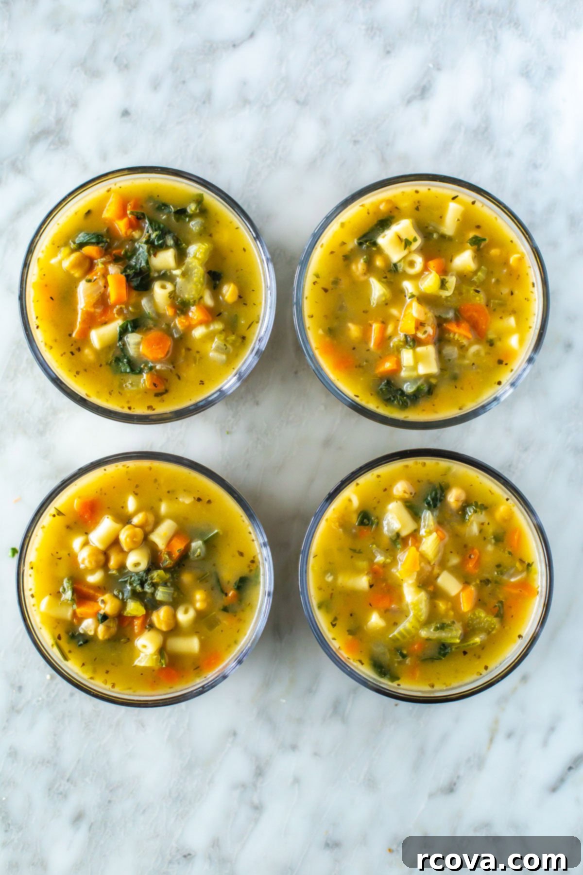 Hearty Chickpea Soup Your Way 10 Four round glass meal prep bowls, each with a serving of chickpea soup inside.