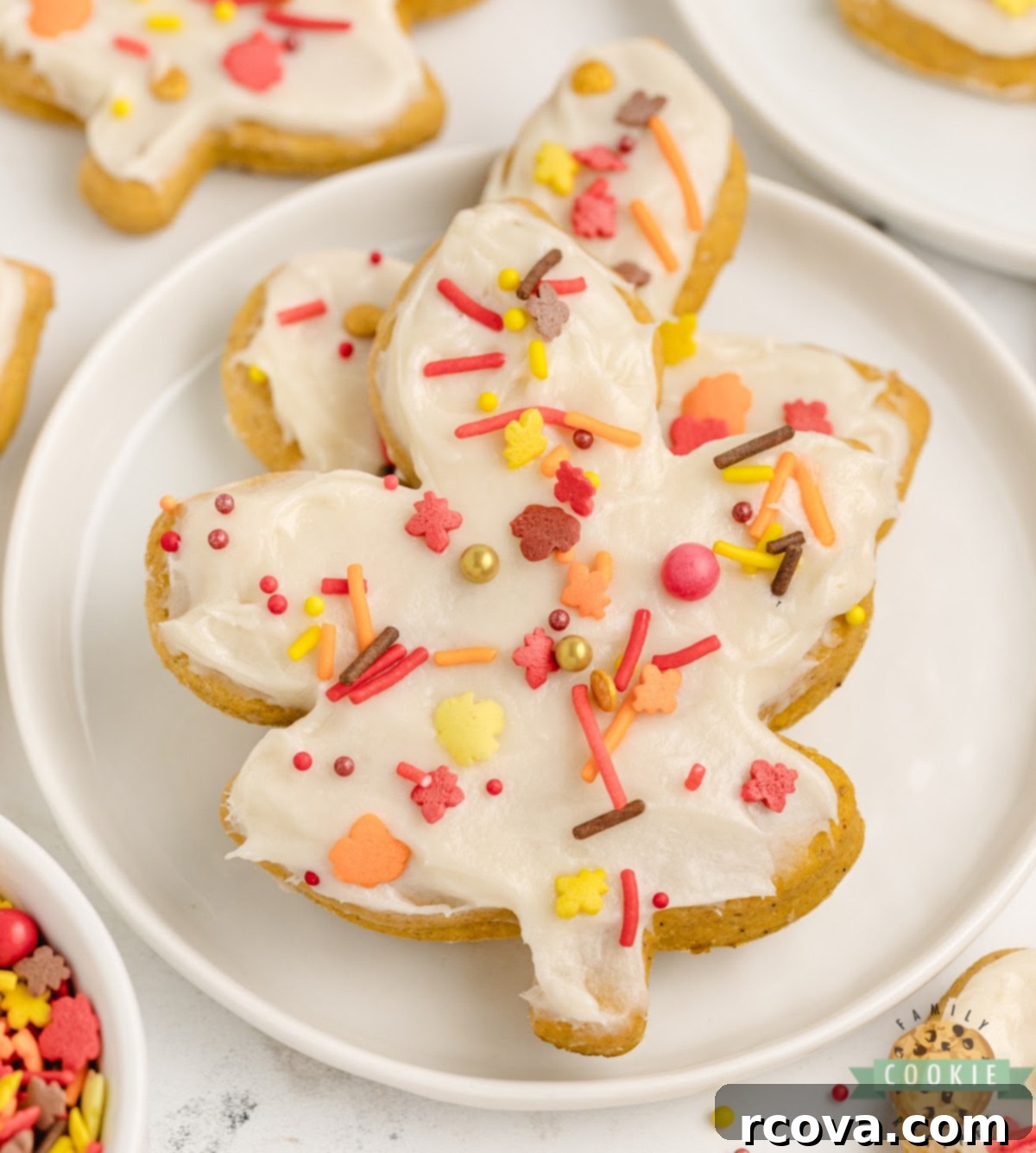 Harvest Pumpkin Sugar Cookie Delights 2 Close-up of frosted Pumpkin Sugar Cookies with cream cheese frosting and sprinkles, showcasing their soft texture.
