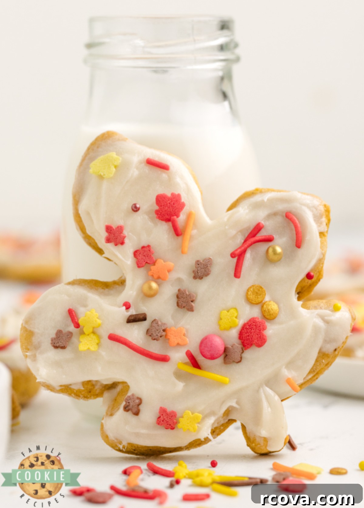 Harvest Pumpkin Sugar Cookie Delights 7 A beautifully decorated Pumpkin Sugar Cookie with cream cheese frosting and a glass of milk in the background.