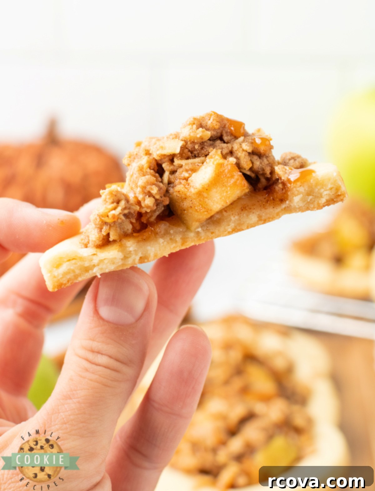 Spiced Apple Crumble Cookies 5 A hand holding a half-eaten Apple Crumble Cookie, showing the soft cookie base, apple filling, and oat crumble.