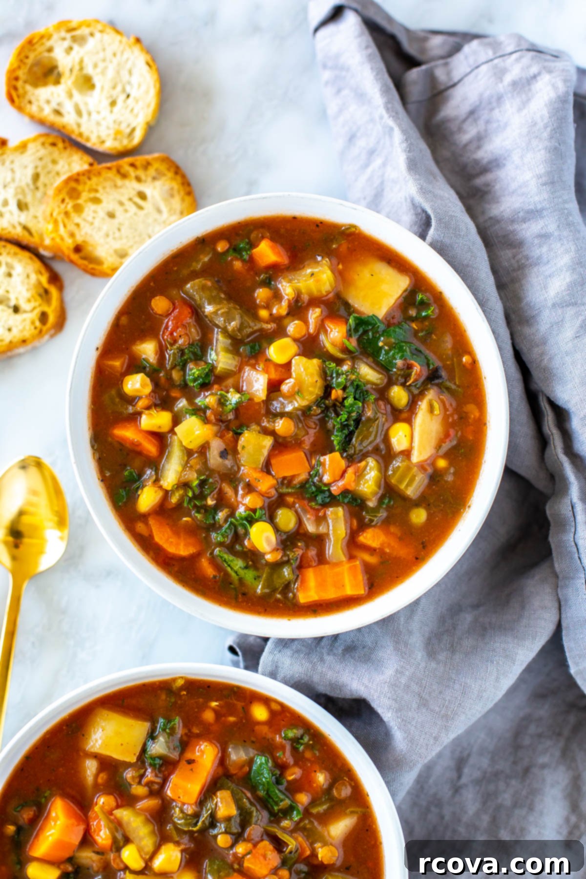 Comforting Crockpot Vegetable Soup 8 A mouthwatering close-up of two bowls of crockpot vegetable soup, served with crusty toasted baguette slices on the side, inviting a warm and comforting meal.