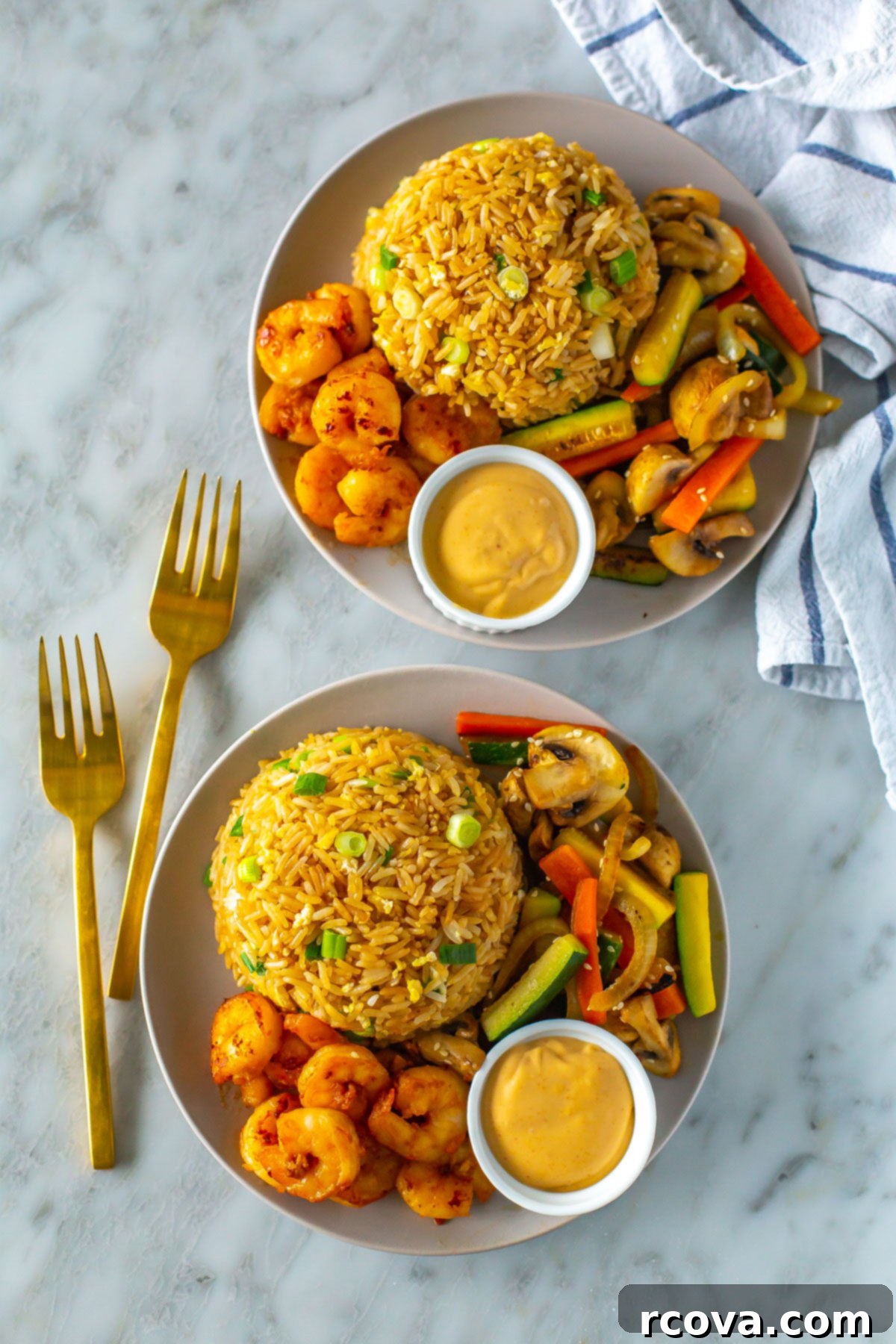Perfect Benihana Style Hibachi Shrimp 2 Two plates of delicious homemade hibachi shrimp, each with a generous side of creamy yum yum sauce, fried rice, and mixed vegetables.