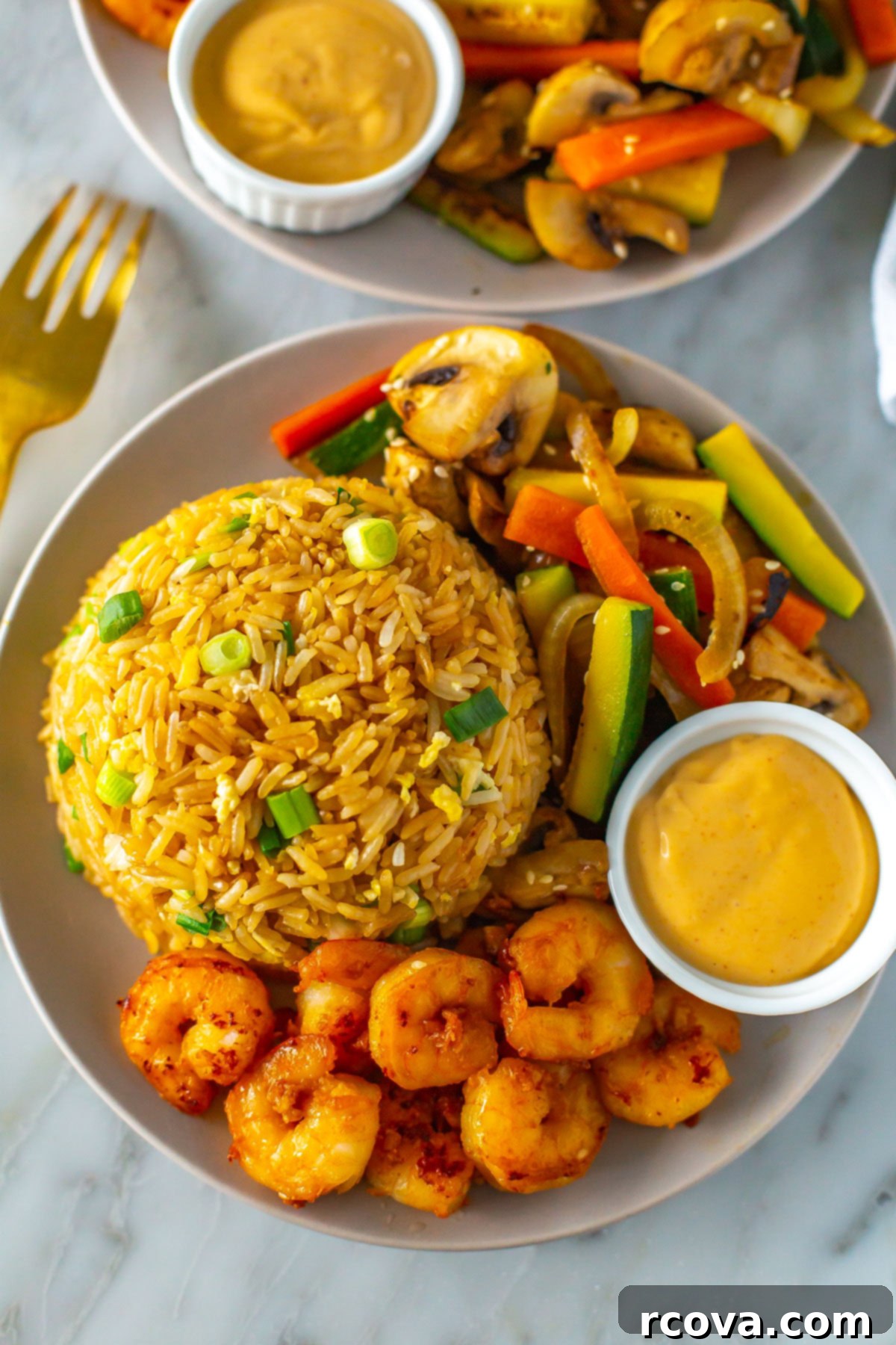 Perfect Benihana Style Hibachi Shrimp 9 A close-up of a single serving of hibachi shrimp, showing the succulent shrimp glistening with sauce, resting atop fluffy fried rice, surrounded by colorful, tender-crisp vegetables.