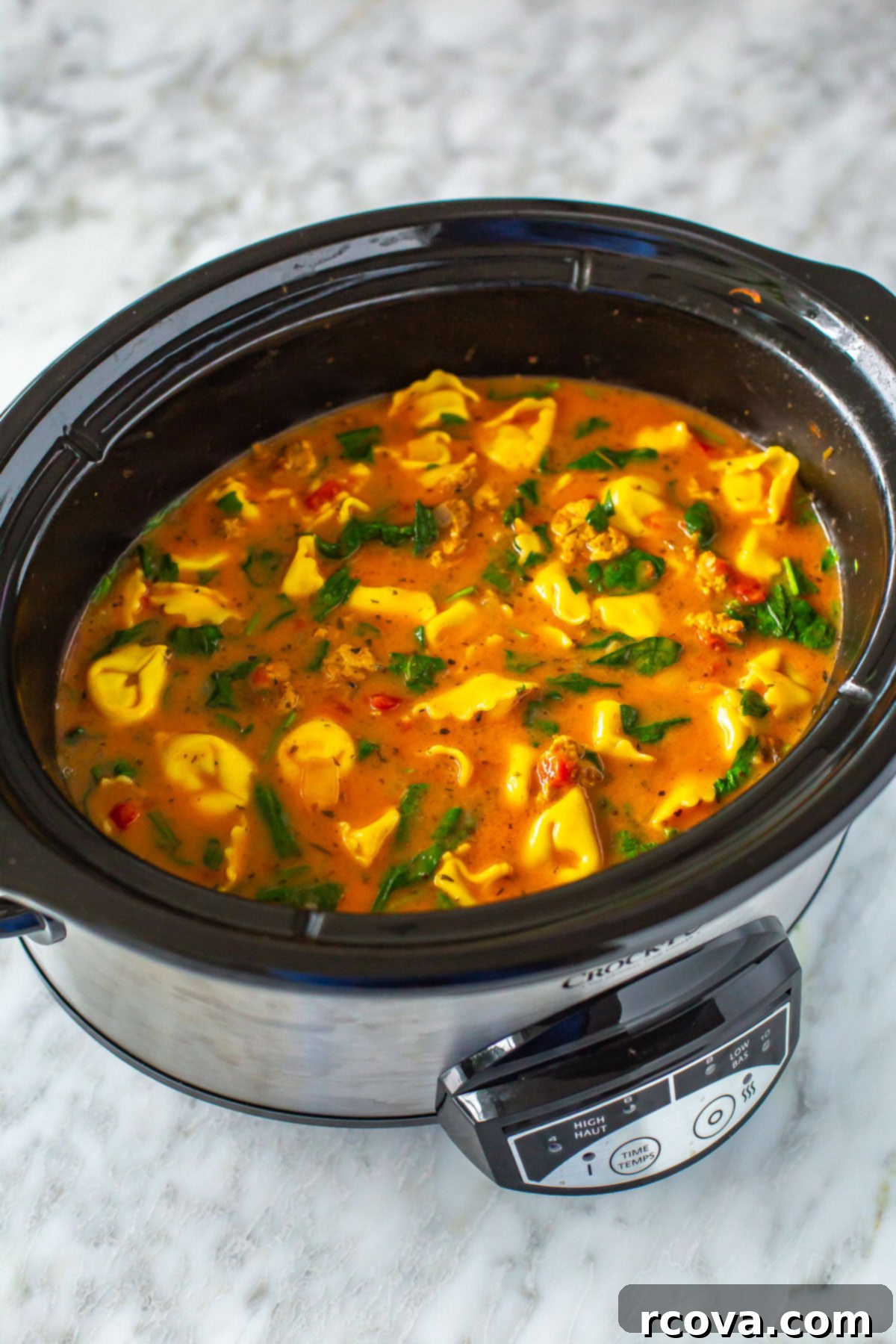 Hearty Crockpot Sausage Tortellini Soup 8 A slow cooker brimming with a rich, creamy crockpot tortellini soup, ready to be served.