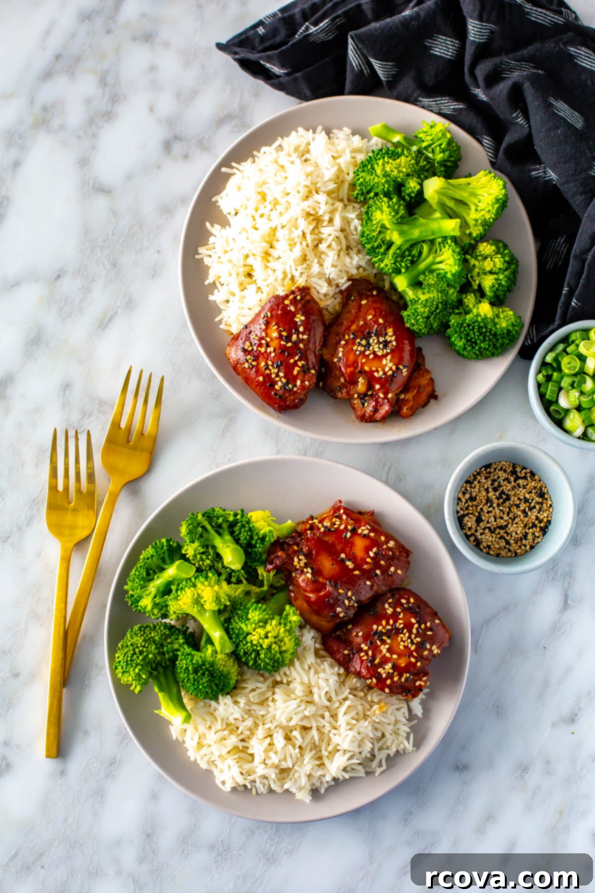 Honey Garlic Slow Cooker Chicken 2 Two plates with slow cooker honey garlic thighs served with rice and broccoli, garnished with green onions and sesame seeds.