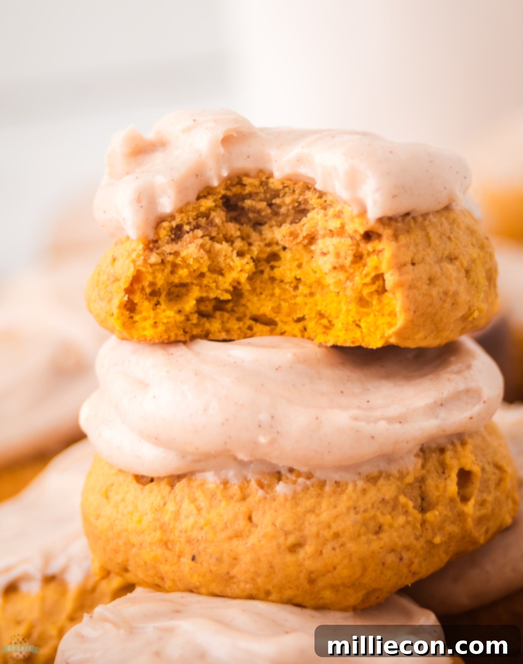 Cream Cheese Frosted Pumpkin Cookies 6 bite taken out of a frosted pumpkin cookie