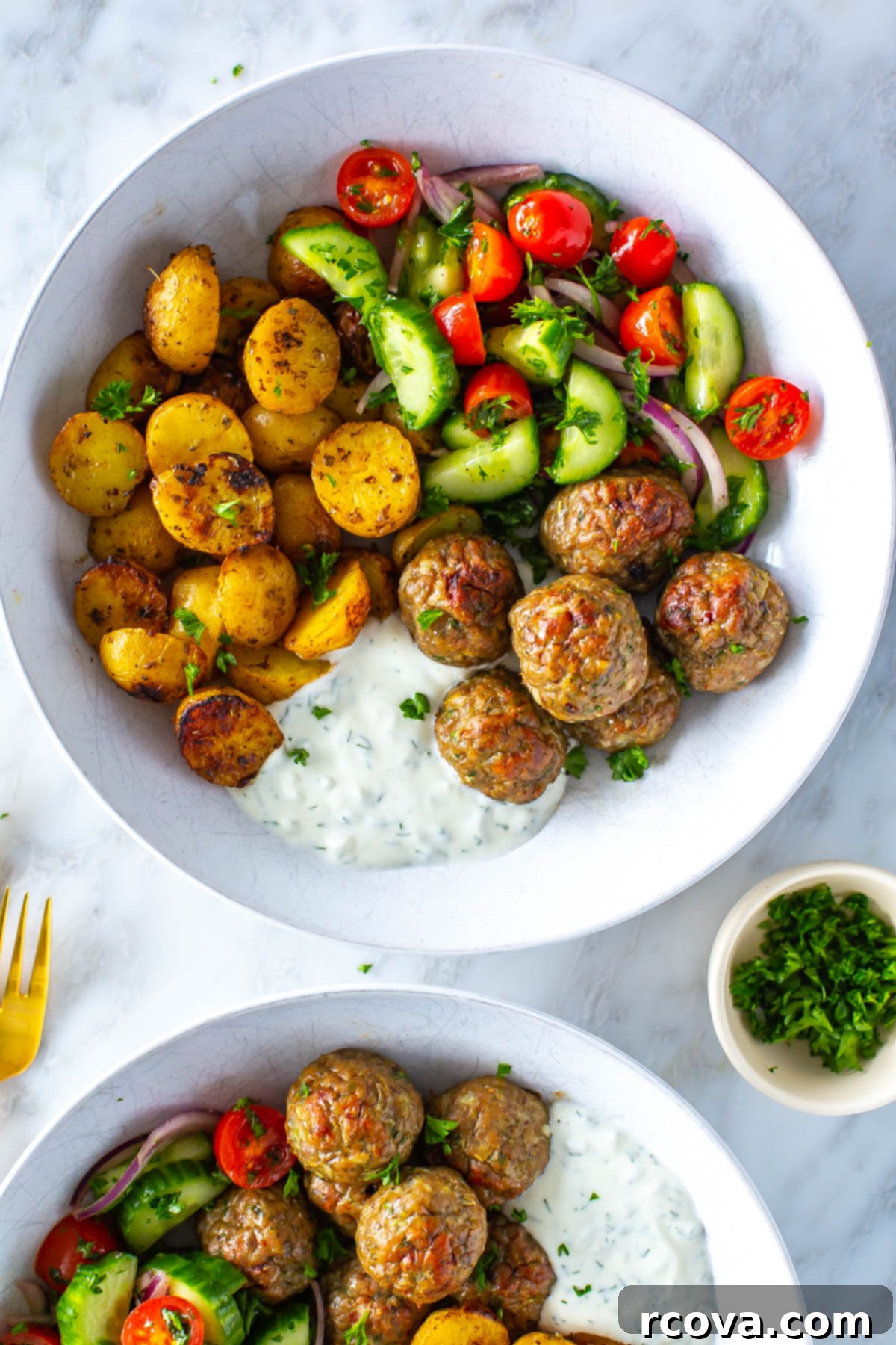 Oven-Roasted Greek Meatballs and Tangy Tzatziki 8 A close-up of a bowl of greek chicken meatballs with a side of potatoes, veggies and tzatziki.