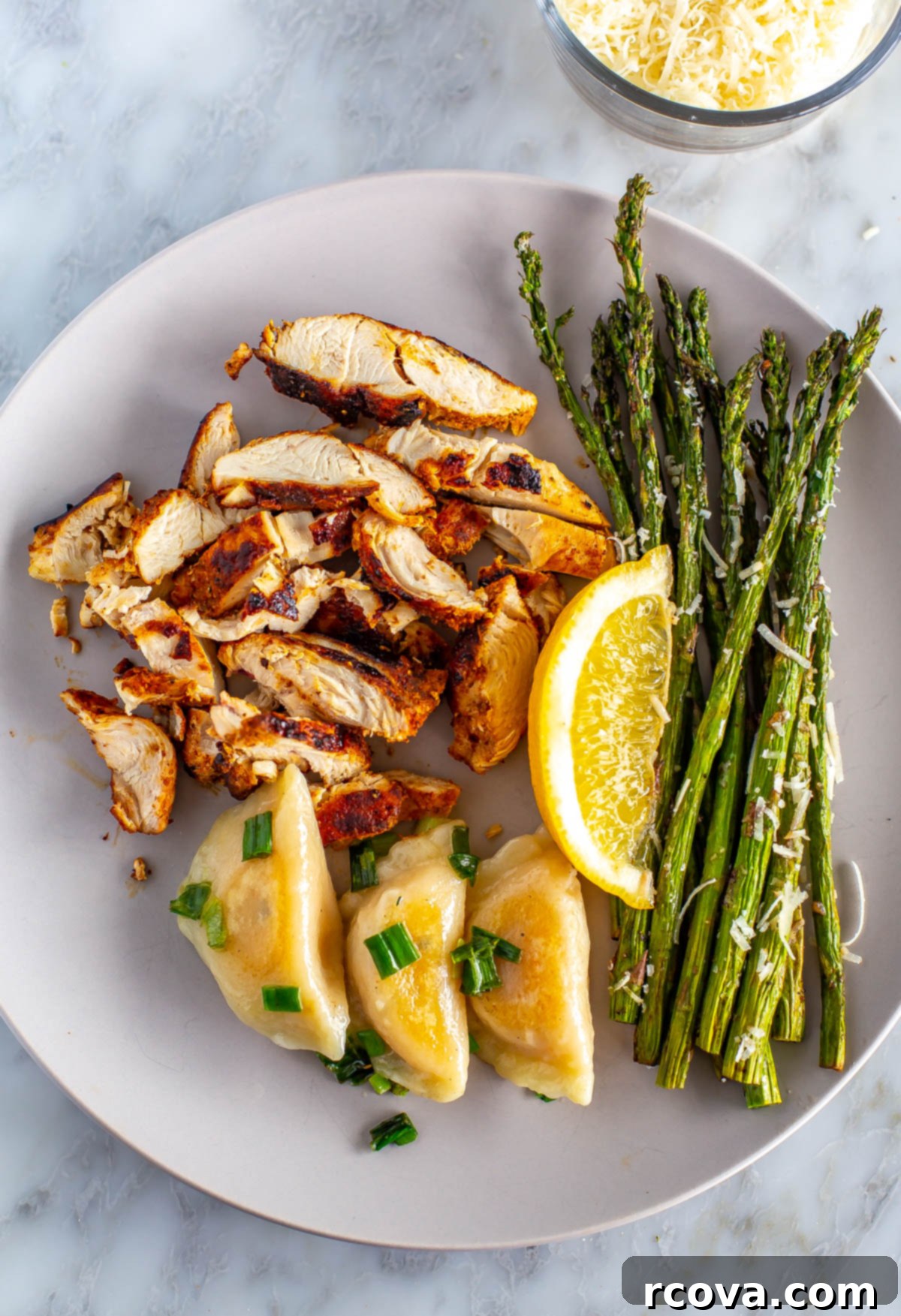 Crispy Air Fryer Asparagus 8 A plate with crispy air fryer asparagus served alongside juicy cut-up chicken breasts and soft dumplings, forming a complete meal.