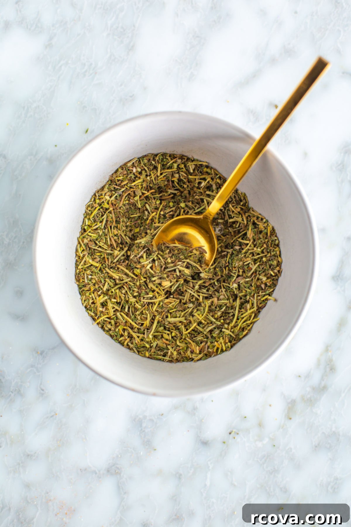 Effortless Homemade Italian Seasoning Never Buy Again 6 Homemade Italian seasoning mixed in a bowl with a spoon, ready for jar storage