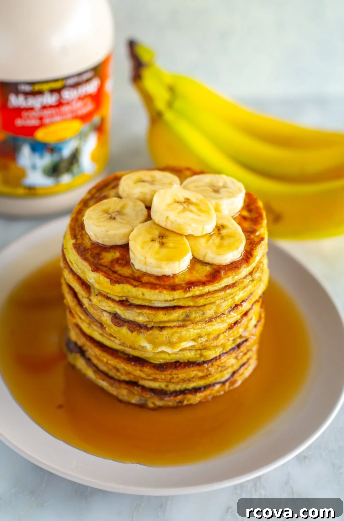 35+ Healthy and Easy Recipes Under 500 Calories 7 A mouth-watering close-up of golden banana egg pancakes, generously drizzled with maple syrup, ready to be enjoyed.