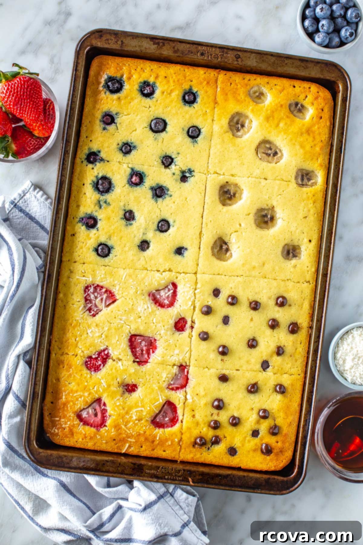 Sheet Pan Pancakes 4 Ways 8 Close-up of baked sheet pan pancakes with strawberries, blueberries, chocolate chips, and banana slices.