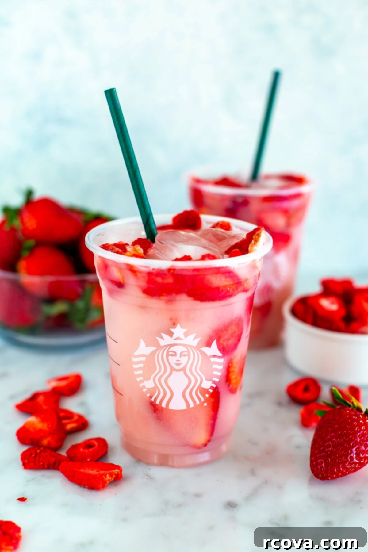 Make Your Own Starbucks Summer Drinks At Home 6 Two cups of homemade Starbucks Pink Drink with freeze-dried strawberries scattered around.