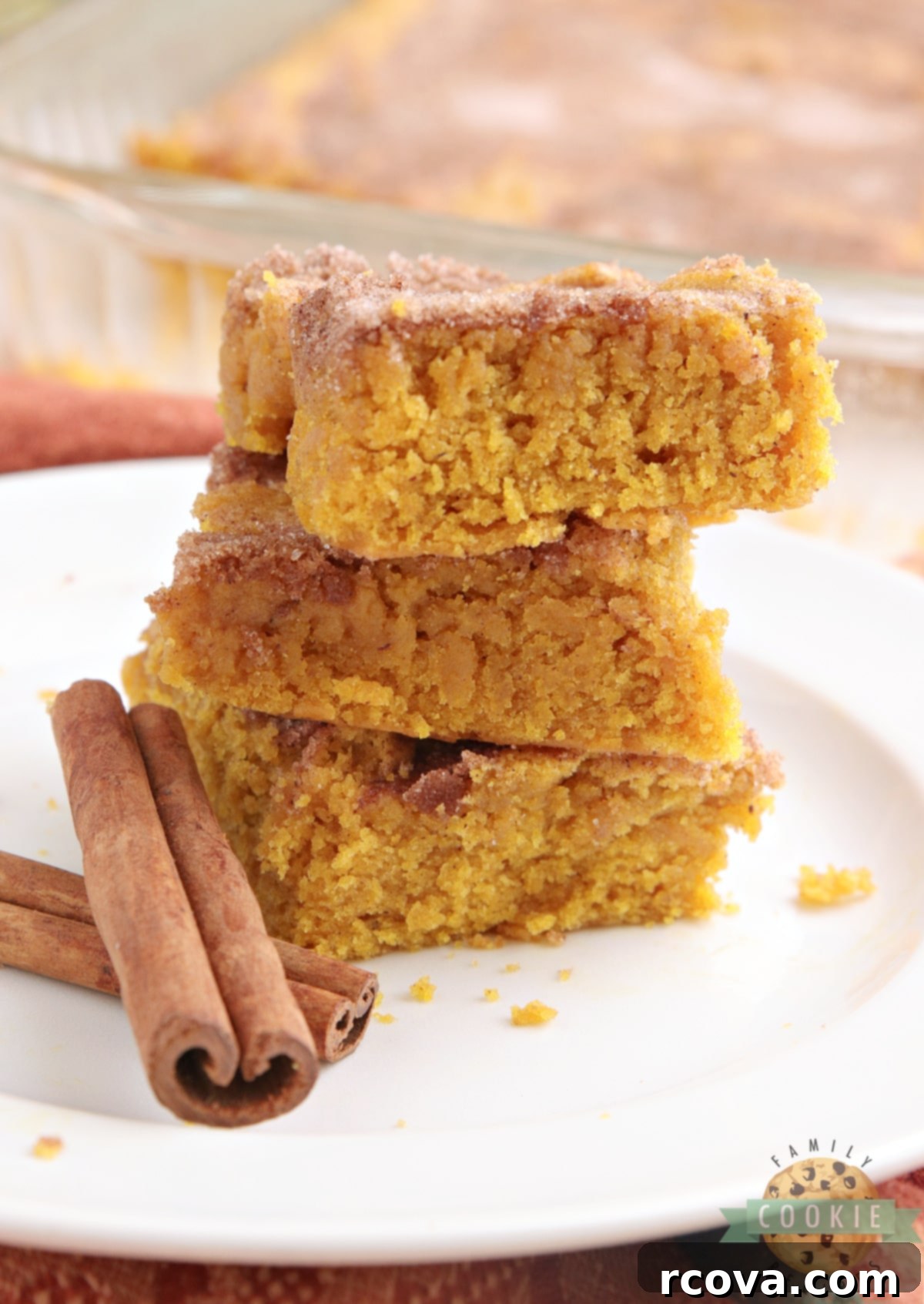 Irresistible Pumpkin Snickerdoodle Bars 3 Pumpkin cookie bars stacked on a plate with cinnamon sugar topping.