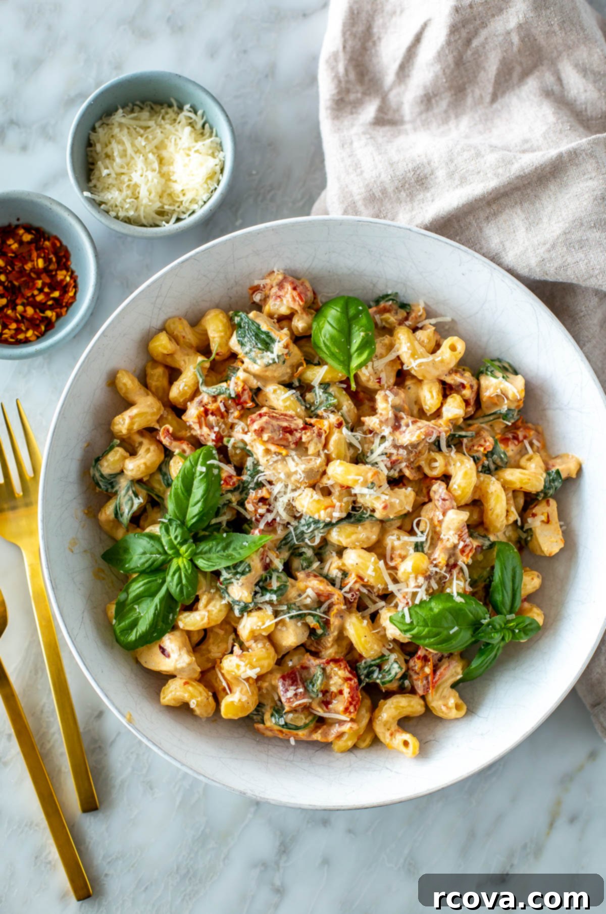 Effortless Creamy Sun-Dried Tomato Pasta 8 A beautifully presented bowl of creamy sundried tomato pasta, topped with grated parmesan cheese and a sprinkle of red chili flakes, highlighting its rich texture and vibrant colors.
