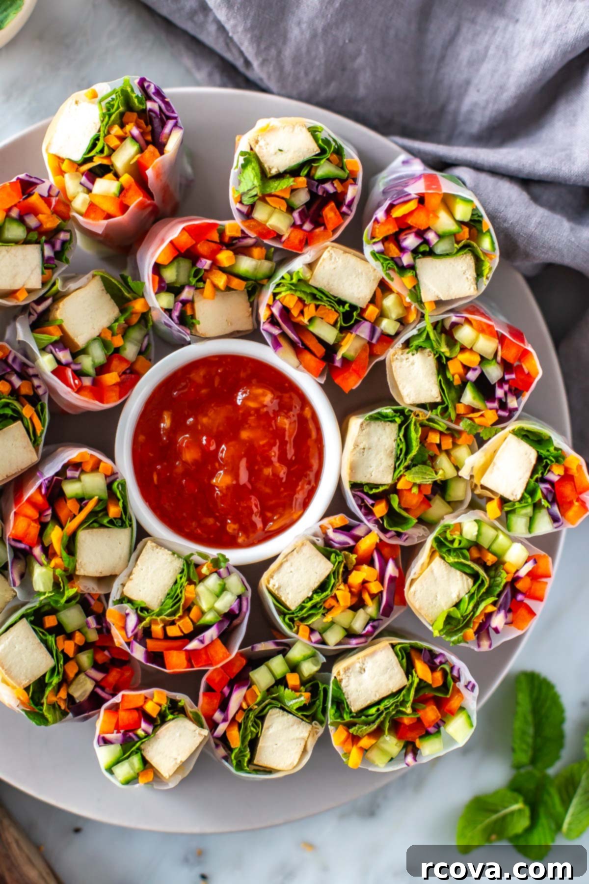 Plant-Powered Summer Rolls with Zesty Chili Dip 8 A close-up of a plate with summer rolls on it with a bowl of sweet chili sauce in the middle.