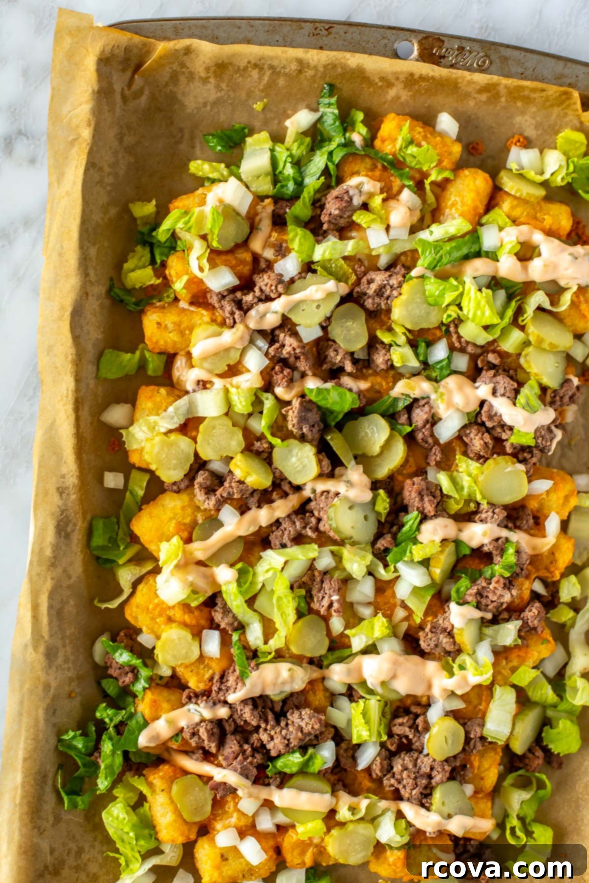 Simple Potluck Showstoppers 27 A close-up of big mac tater tot nachos on a baking sheet covered with parchment paper.
