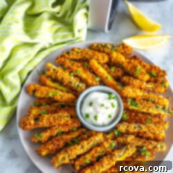 Perfectly Crispy Air Fryer Zucchini Fries 11 A plate of air fryer zucchini fries with garlic aioli in front of an air fryer.