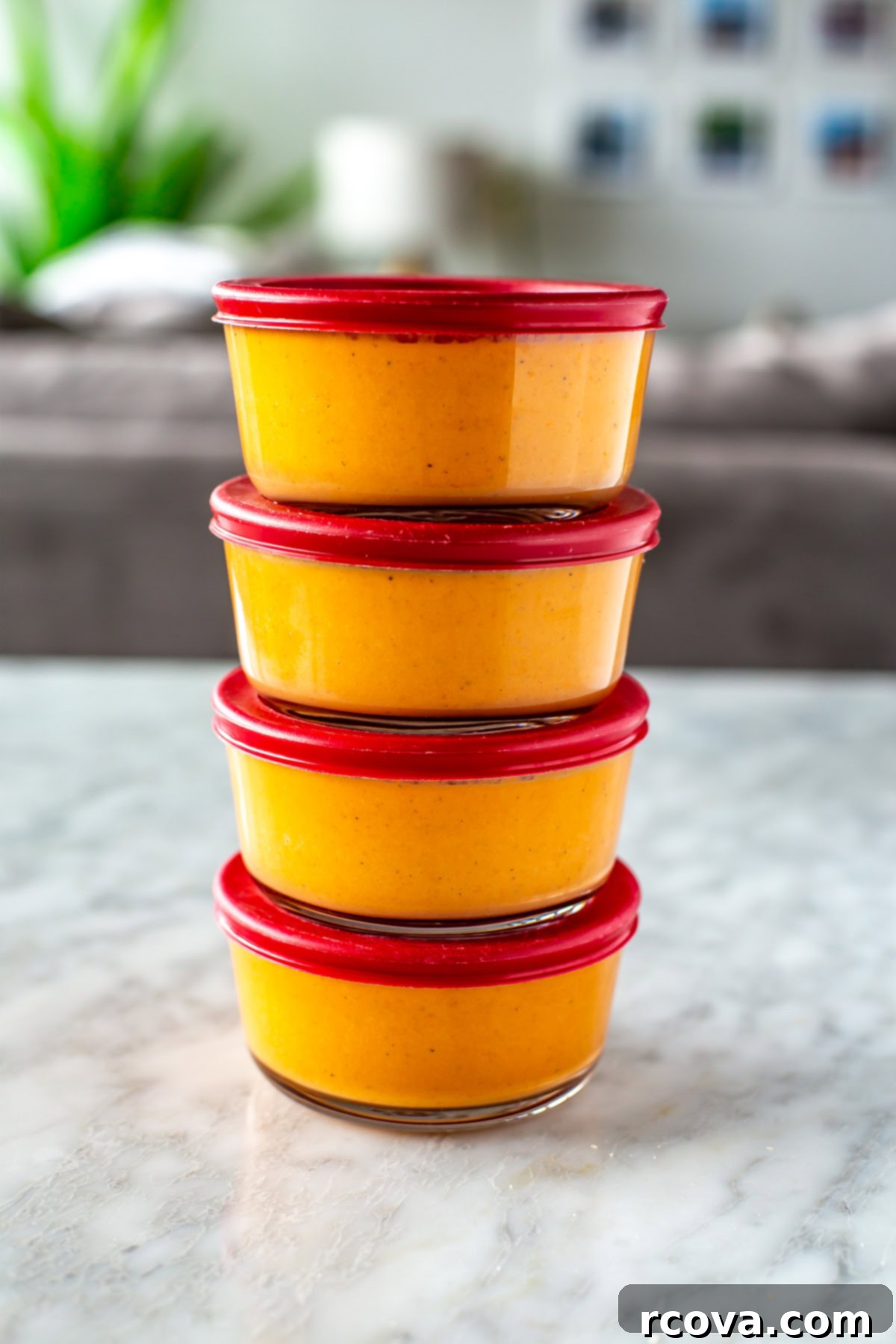 Sun-Kissed Roasted Tomato Basil Bliss 9 Four round glass meal prep containers, perfectly stacked, each holding a serving of vibrant roasted tomato basil soup, ready for easy storage and future enjoyment.