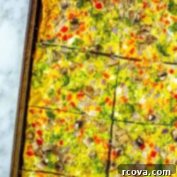 Big Batch Sheet Pan Eggs 11 A beautifully baked sheet pan of eggs, cut into squares, and loaded with colorful vegetables, perfect for a hearty and convenient breakfast.