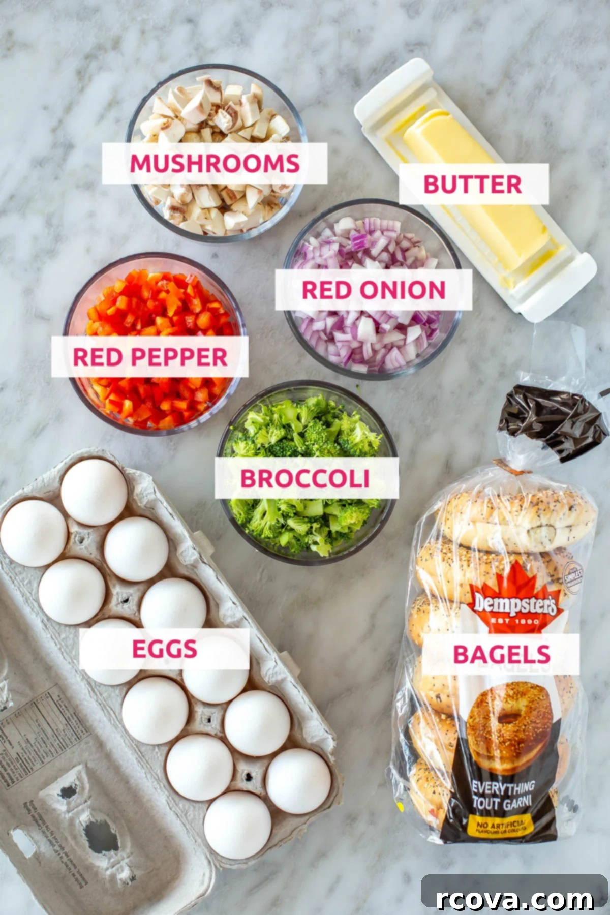 Big Batch Sheet Pan Eggs 4 Fresh ingredients laid out for making sheet pan eggs, including a carton of eggs, chopped broccoli, vibrant red bell pepper, thinly sliced red onion, sliced mushrooms, a stick of butter, and a couple of plain bagels.