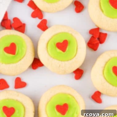 The Grinch's Thumbprint Delights 7 Grinch Thumbprint Cookies with green filling and red heart