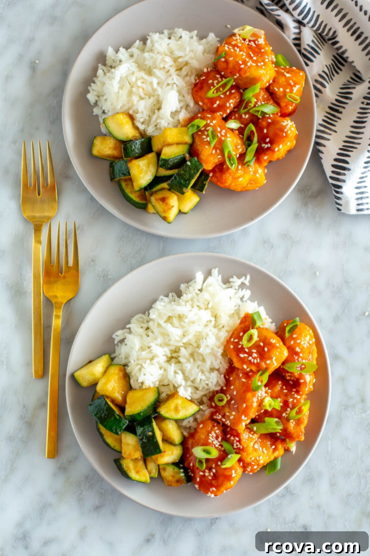 Explosive Firecracker Chicken Dinner 2 Two plates of vibrant firecracker chicken, perfectly sauced, served alongside fluffy white rice and tender sautéed zucchini.