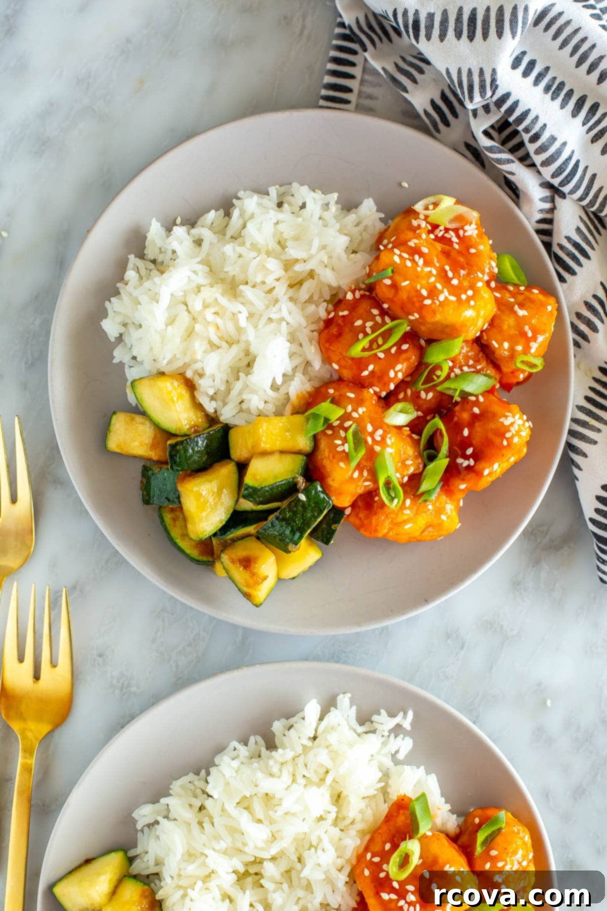 Explosive Firecracker Chicken Dinner 8 A beautifully plated dish of Firecracker Chicken, glistening with its signature sweet and spicy sauce, accompanied by white rice and sautéed zucchini.
