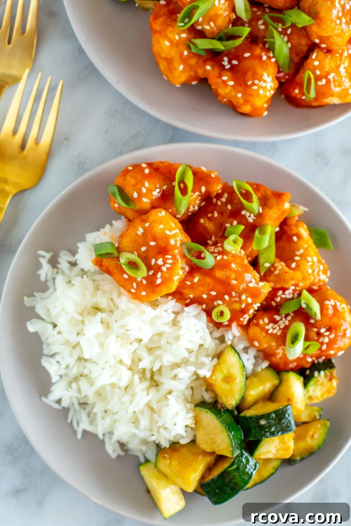 Explosive Firecracker Chicken Dinner 9 A close-up shot of a single plate of Firecracker Chicken with rice and sautéed zucchini, highlighting the succulent chicken and vibrant sauce.