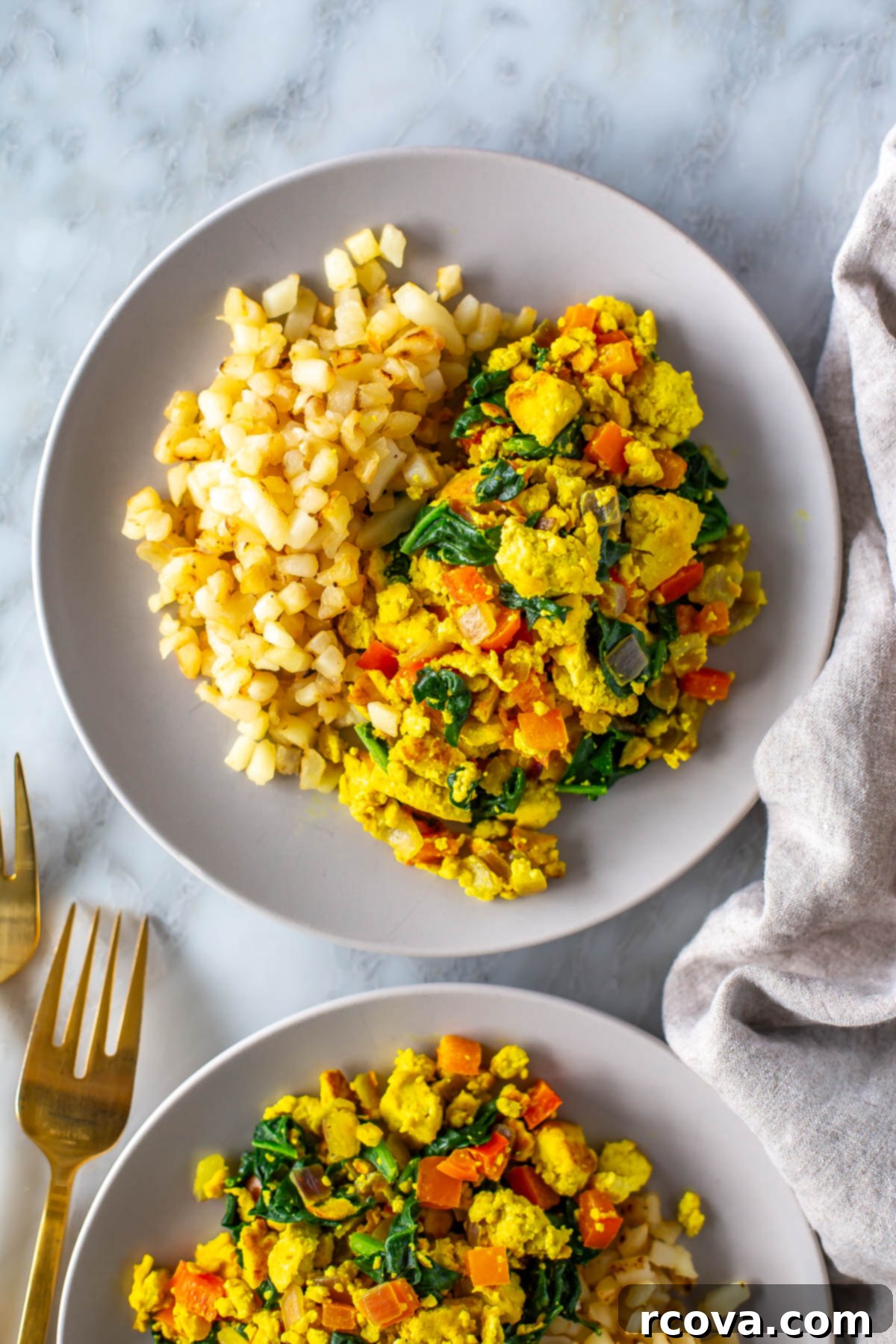 Garden-Fresh Tofu Scramble 7 A close-up shot of a plate of fluffy and colorful tofu scramble, served alongside perfectly golden-brown hashbrowns, ready to be enjoyed as a hearty vegan breakfast.