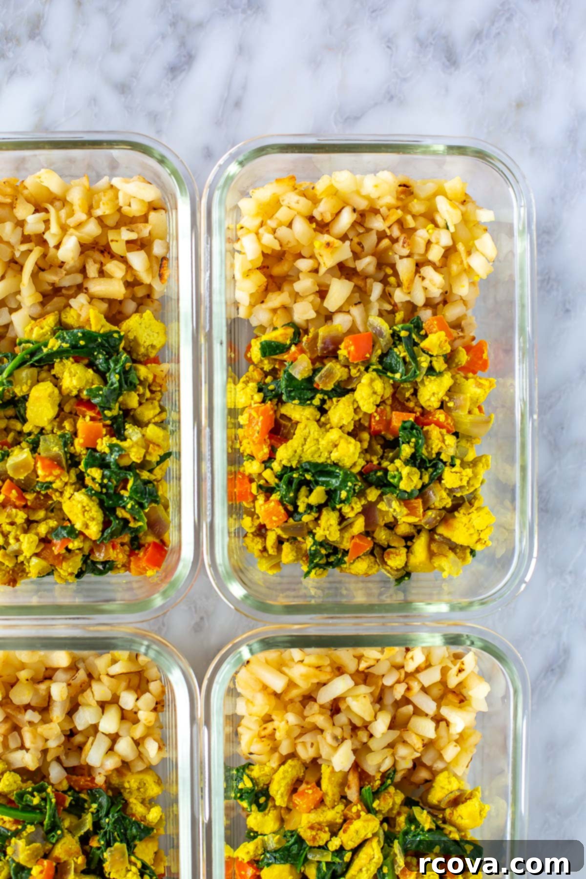 Garden-Fresh Tofu Scramble 8 A vibrant close-up of a glass meal prep bowl filled with vegan tofu scramble and a generous portion of hashbrowns, ready for a healthy and convenient meal.