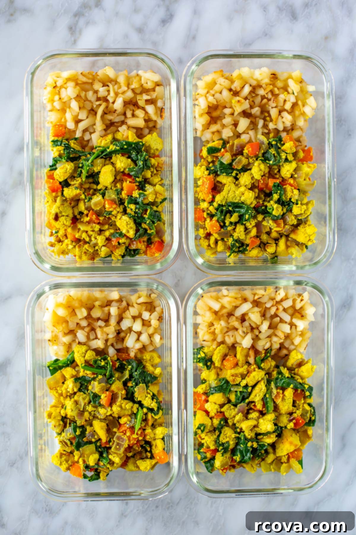 Garden-Fresh Tofu Scramble 9 Four individual glass meal prep containers, each perfectly portioned with a serving of fluffy tofu scramble and crispy hashbrowns, ready for the week ahead.