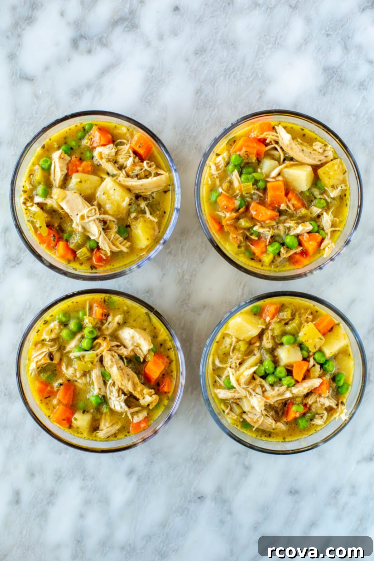 Wholesome Chicken Pot Pie Soup 10 Four round meal prep containers filled with generous servings of healthy chicken pot pie soup, ready for easy lunches or dinners throughout the week.