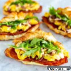 Ready-to-Go Croissant Breakfast Sandwiches 11 Four croissant breakfast sandwiches with bacon, scrambled eggs and arugula inside them.