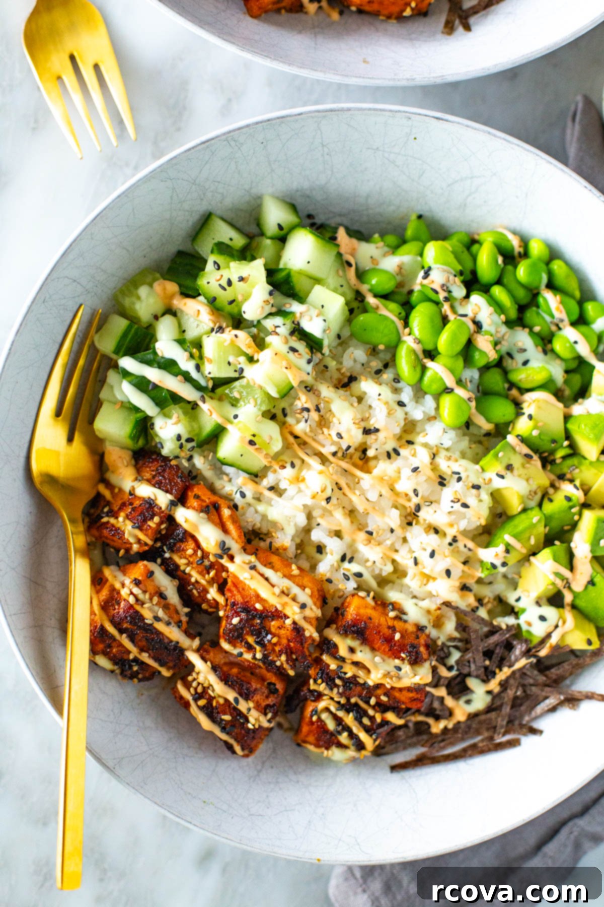 Effortless Spicy Salmon Sushi Bowls 8 A close-up of a beautifully assembled salmon sushi bowl with creamy sauces and fresh vegetables.
