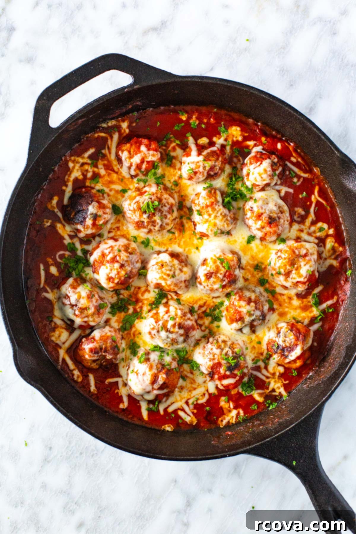 Cheesy Chicken Parmesan Meatballs 2 A skillet of chicken parm meatballs topped with bubbling mozzarella cheese and fresh basil, ready to be served.