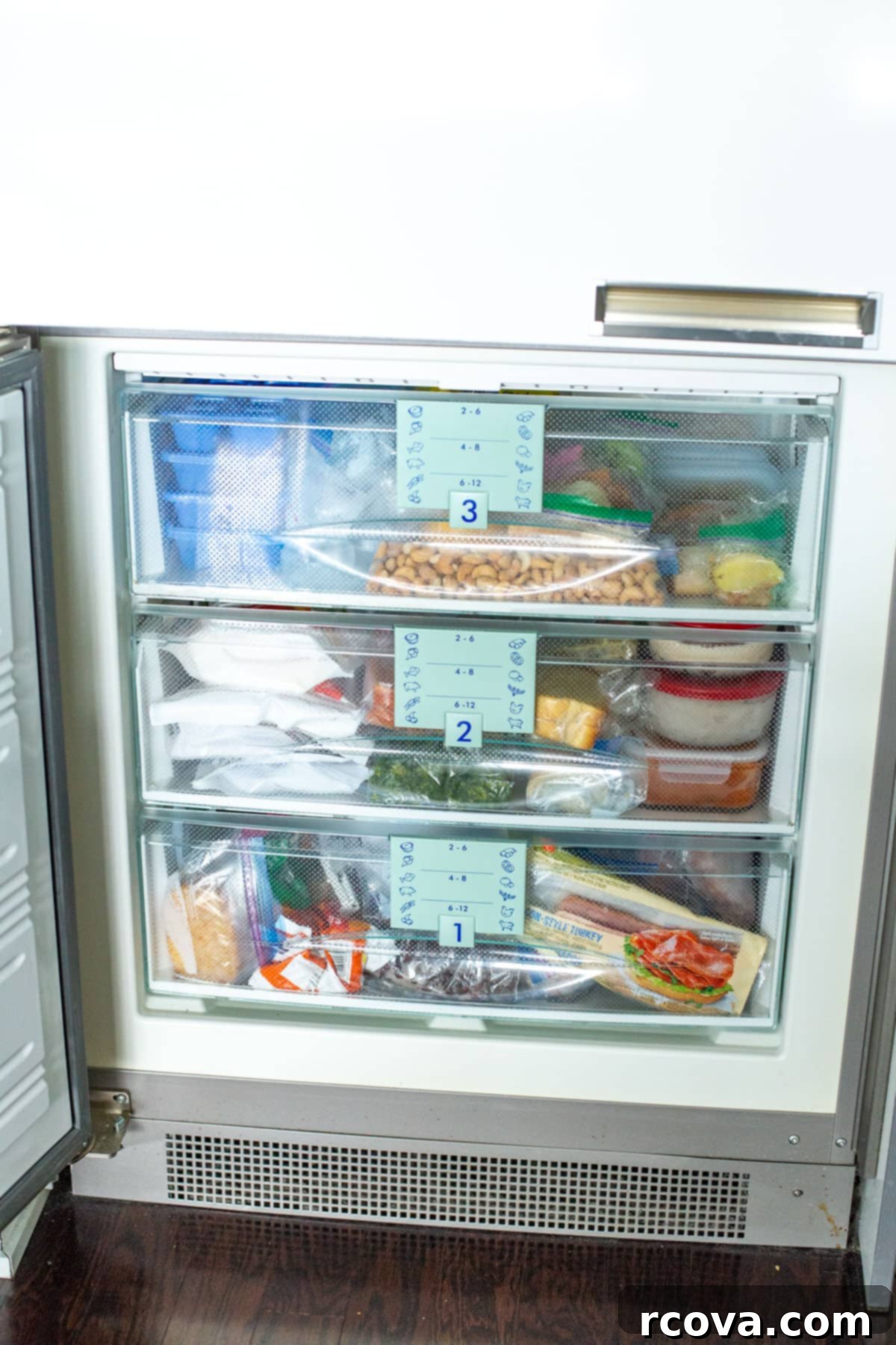 Dondurucuyu Düzenlemenin 6 Kolay Yolu 2 An organized freezer with three clear drawers, showcasing neatly arranged food items.