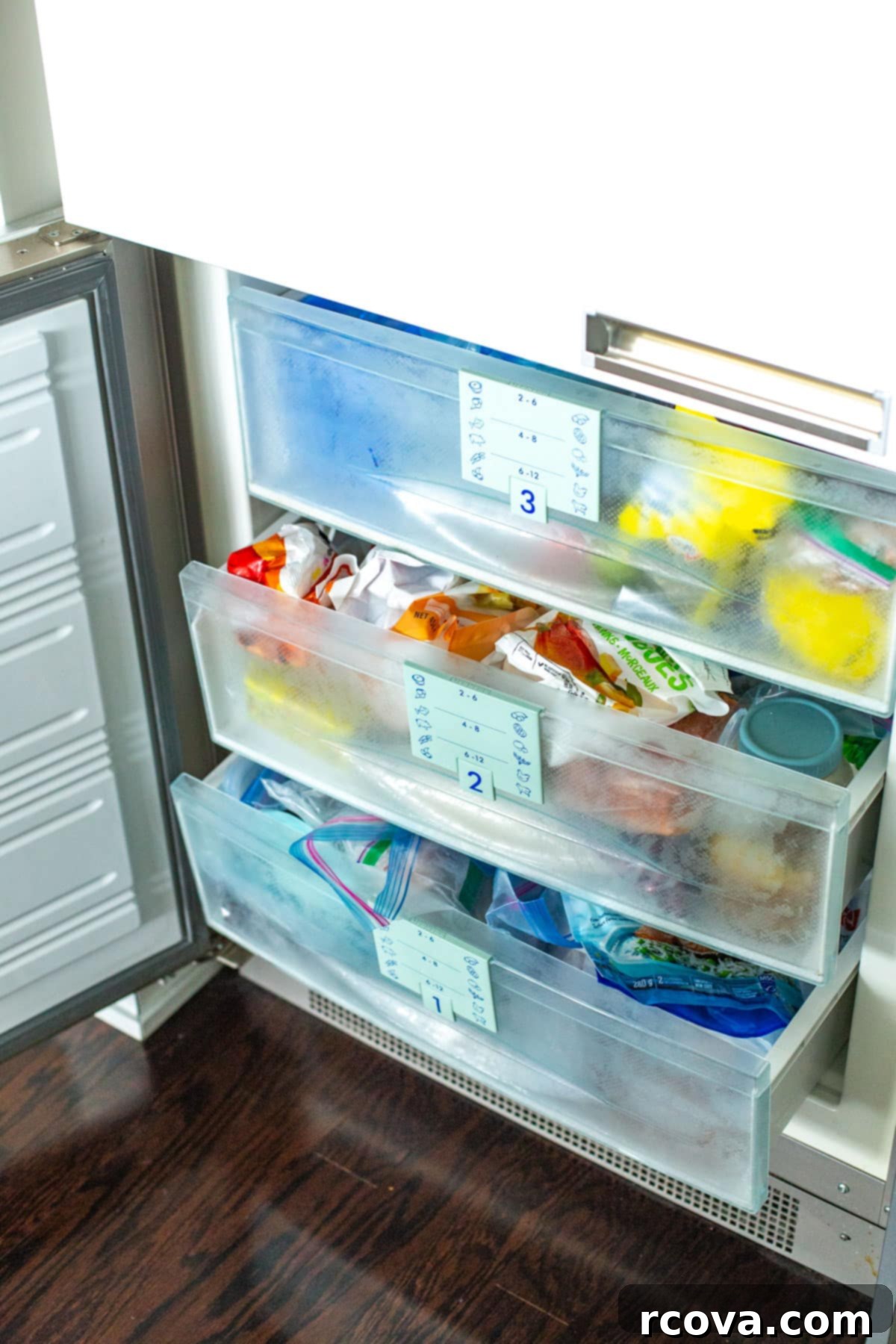 Dondurucuyu Düzenlemenin 6 Kolay Yolu 8 An organized upright freezer with three shelves, neatly stocked with food.