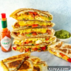 Mastering the Taco Bell Breakfast Crunchwrap at Home 10 Cut open breakfast crunchwraps stacked together with a side of hot sauce and guacamole.
