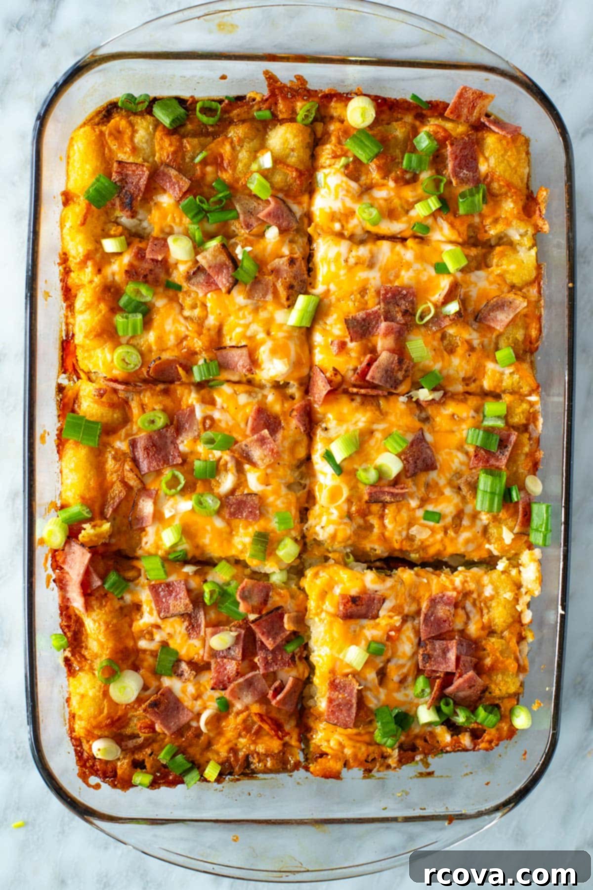 Crunchy Morning Casserole 8 Slices of golden Tater Tot Breakfast Casserole, showcasing the layers of tater tots, eggs, and cheese, topped with bacon and green onions.