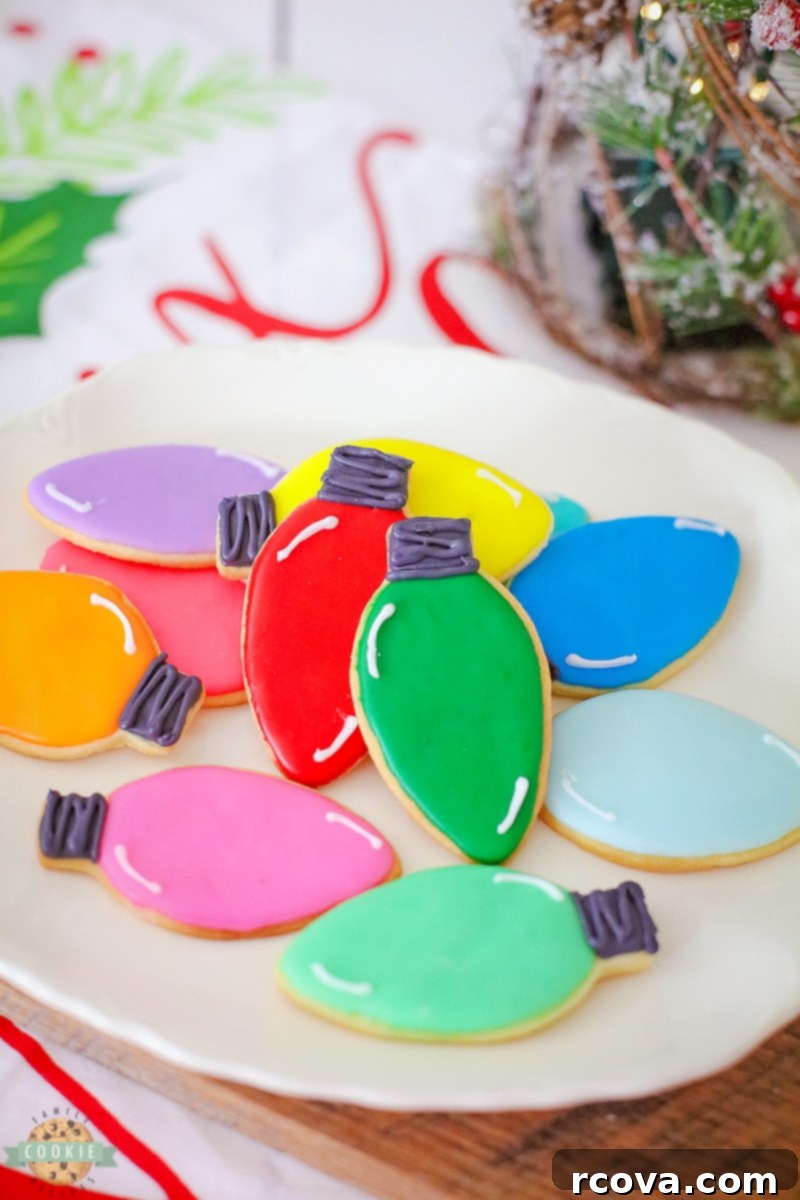 Twinkling Christmas Light Cookies 2 A tray of beautifully decorated Christmas light cut-out cookies, featuring various bright colors and a realistic black base with white highlights.