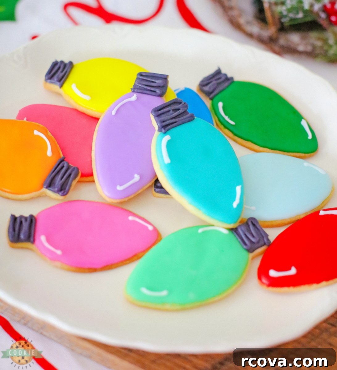 Twinkling Christmas Light Cookies 8 A close-up of a stack of festive Christmas light cut-out cookies, showcasing their bright colors and intricate icing details.