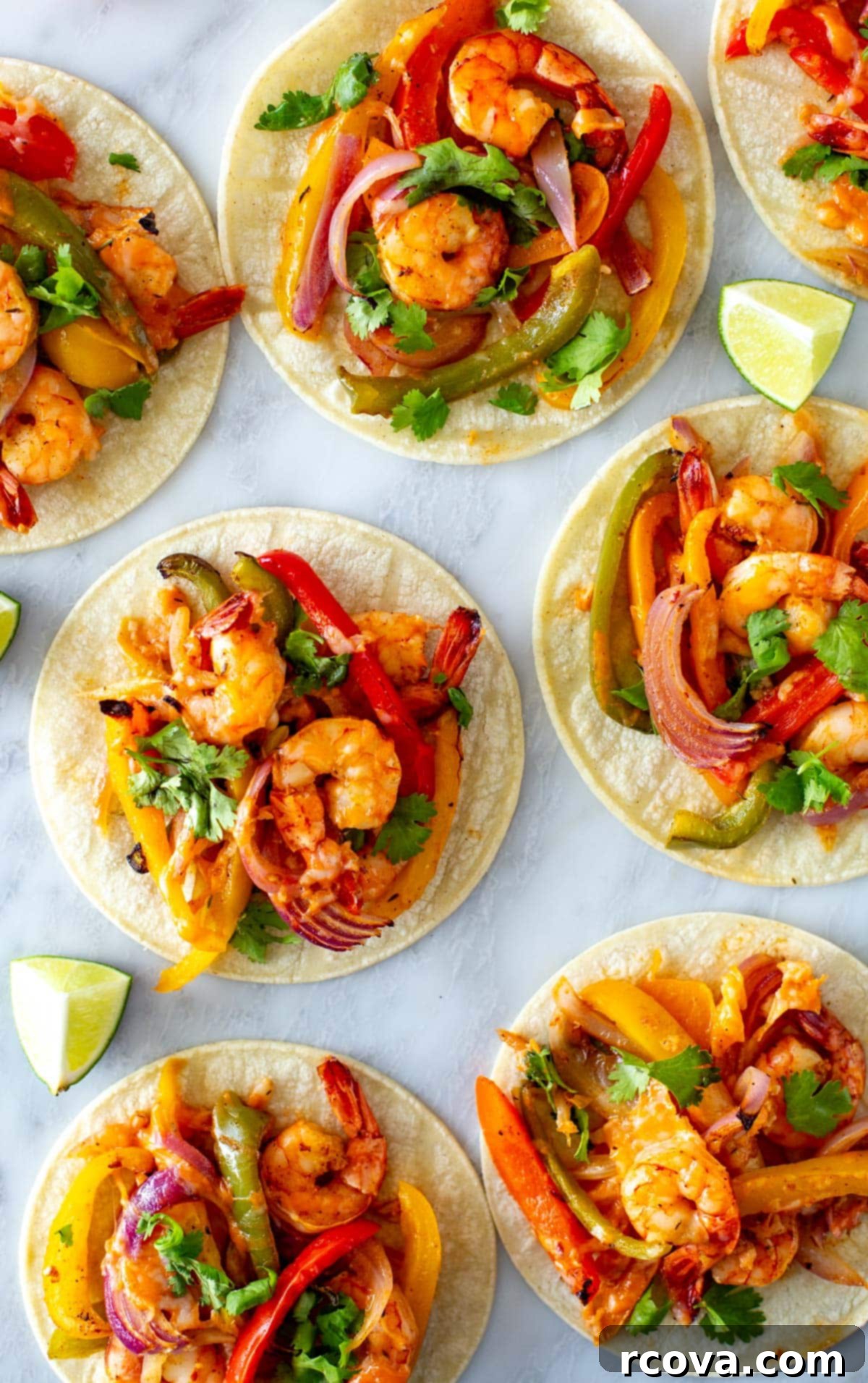 Effortless Sheet Pan Shrimp Fajitas 7 Four corn tortillas filled with sheet pan shrimp fajitas, topped with fresh cilantro, and arranged on a wooden board.