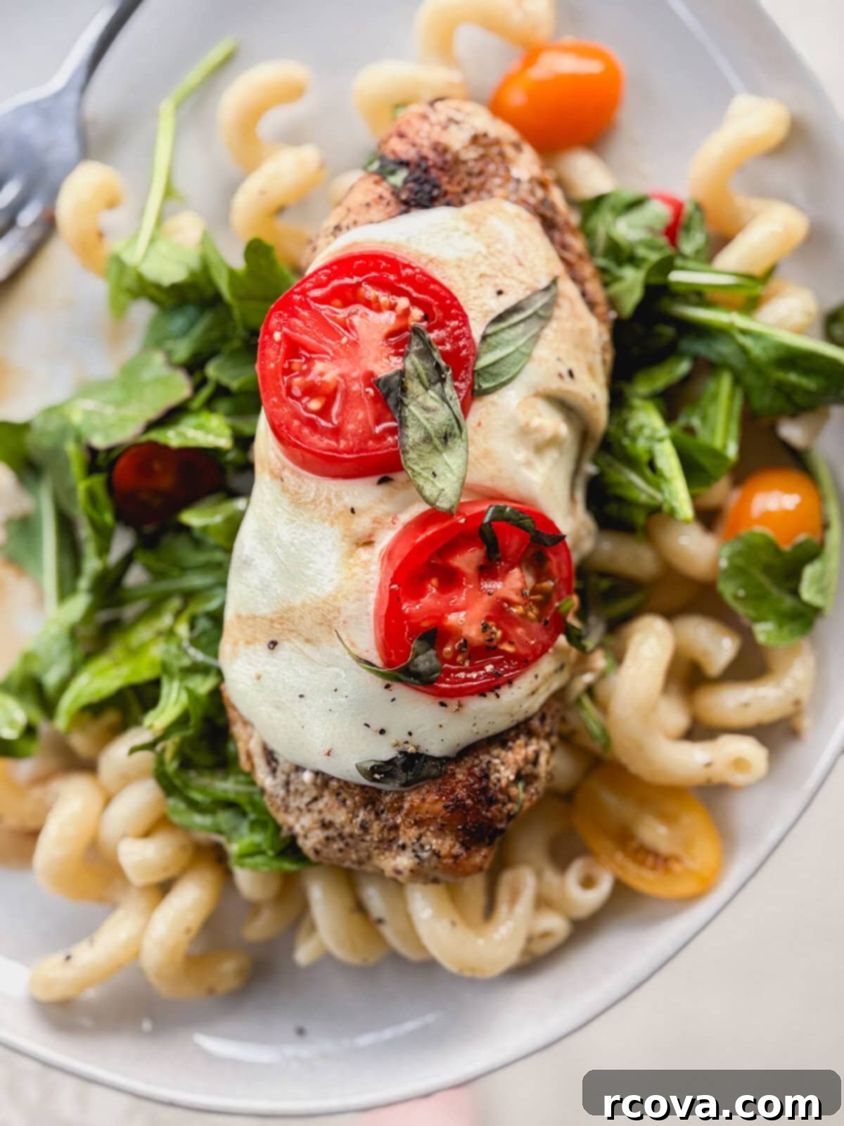 One-Pan Balsamic Caprese Chicken 5 Plated Caprese chicken alongside a fresh arugula pasta salad, garnished with basil.
