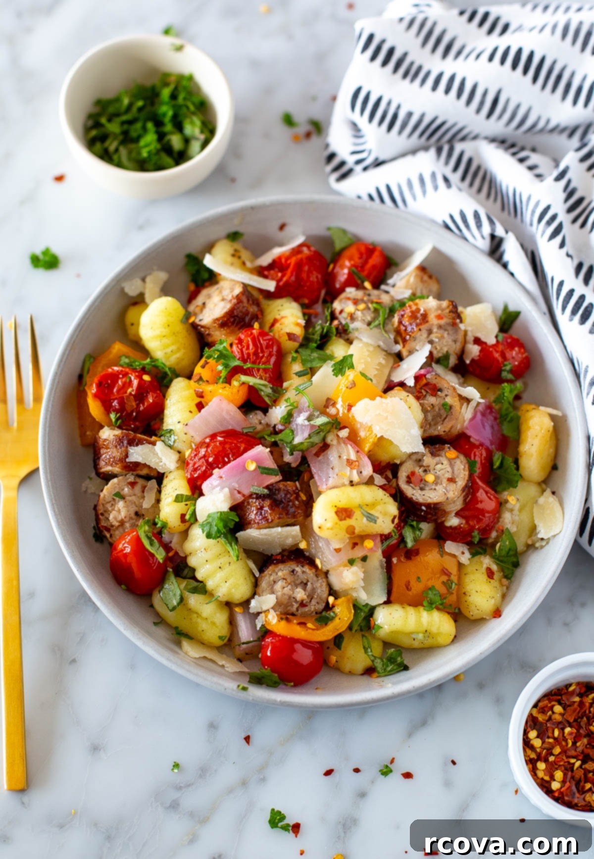 Easy One-Pan Sausage Gnocchi 2 A beautifully cooked sheet pan gnocchi with browned sausage, roasted cherry tomatoes, and colorful bell peppers, garnished with fresh herbs.