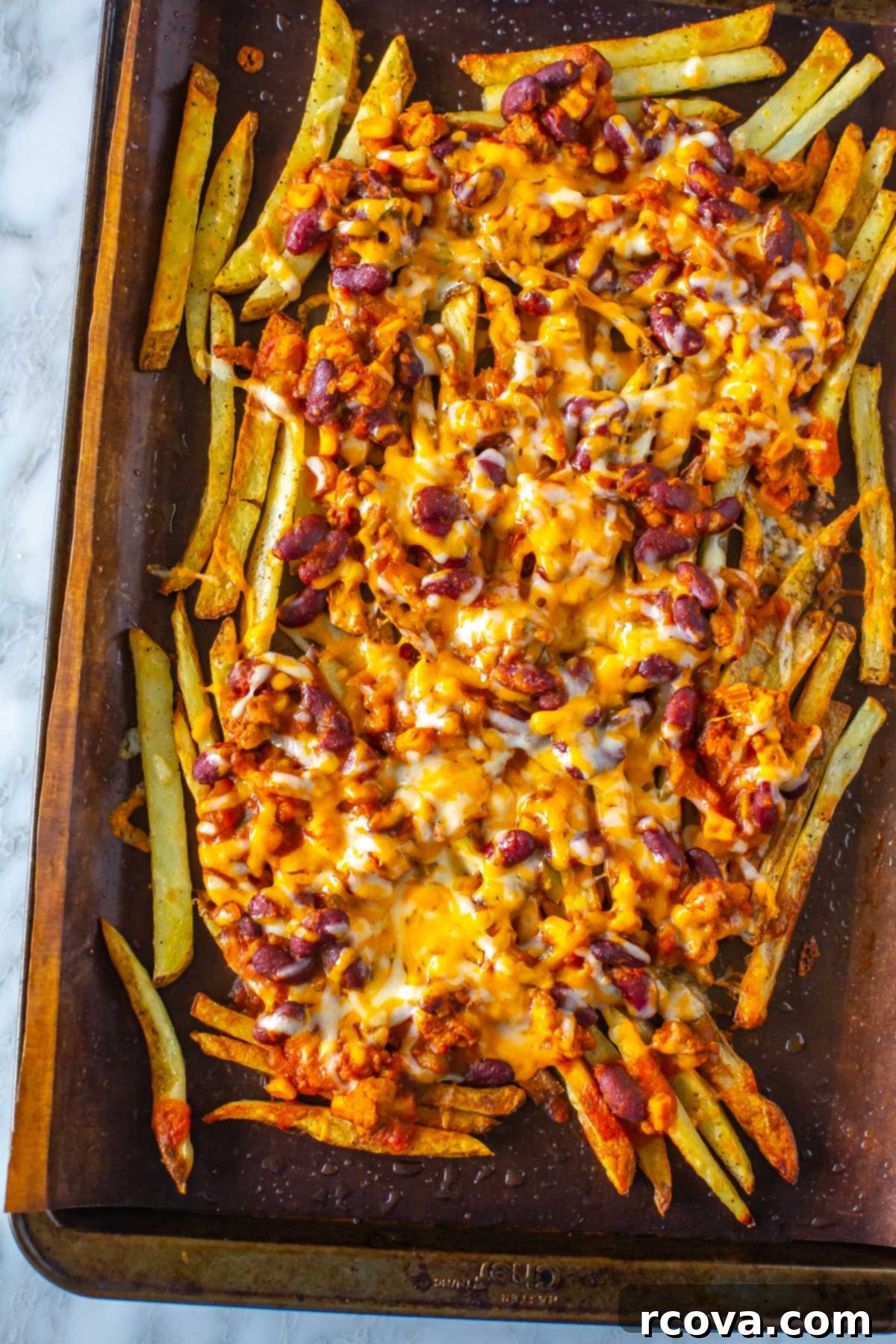 Next-Level Chili Cheese Fries 8 A close-up of chili cheese fries on a sheet pan lined with parchment paper.