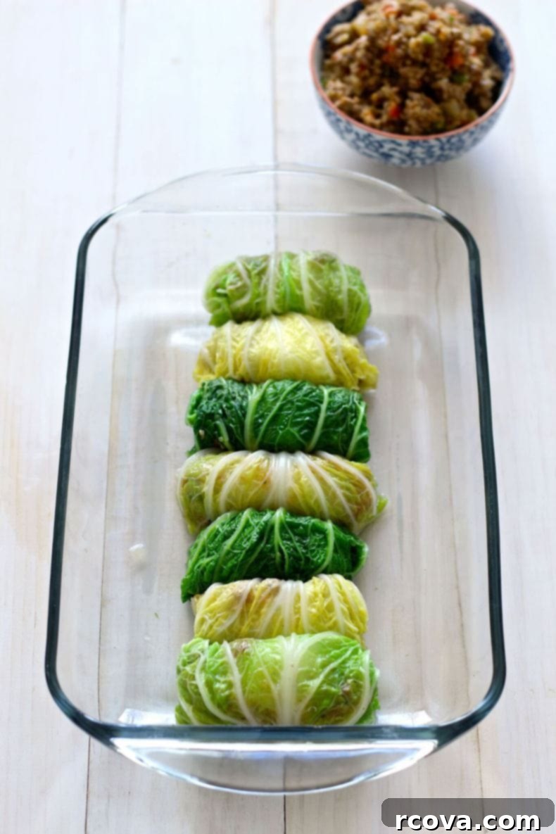 Wholesome Napa Cabbage Wraps 6 Overhead view of several Healthier Napa Cabbage Rolls cooking in a large white casserole dish, generously coated in red tomato sauce, fresh out of the oven.
