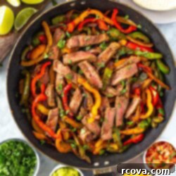 Sizzling Steak Fajitas 11 Overhead shot of vibrant steak fajitas in a cast iron skillet with perfectly seared steak, colorful red and yellow bell peppers, and tender onions. Surrounding the skillet are small bowls of fresh guacamole, tangy sour cream, shredded cheddar cheese, zesty salsa, and warm tortillas, with chopped cilantro and lime wedges nearby.